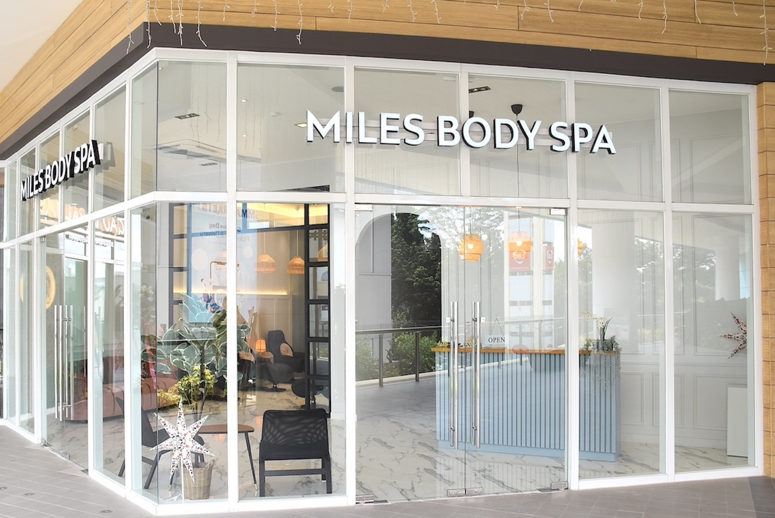 Glass storefront of Miles Body Spa with white framing and a reception desk visible inside, through large glass windows.